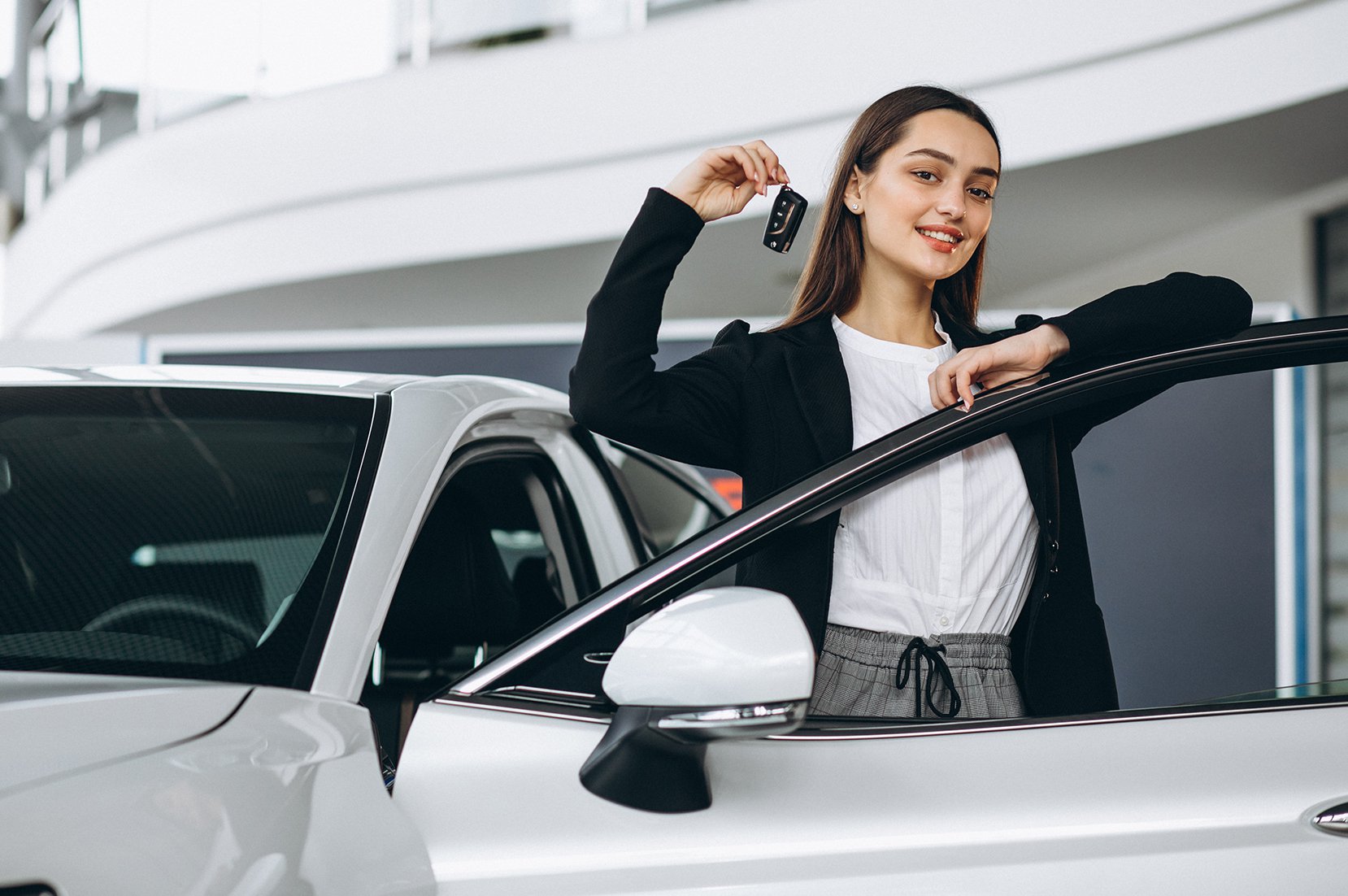 Kobieta trzymająca w dłoni kluczyki stojąca w drzwiach samochodu - przygotowanie auta do sprzedaży